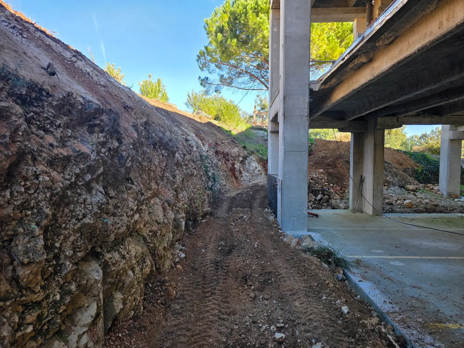 Terrassement d'un talus avec mini-pelle CAT, agrandissement de surlargeur, terrain en pente, préparation pour travaux futurs.