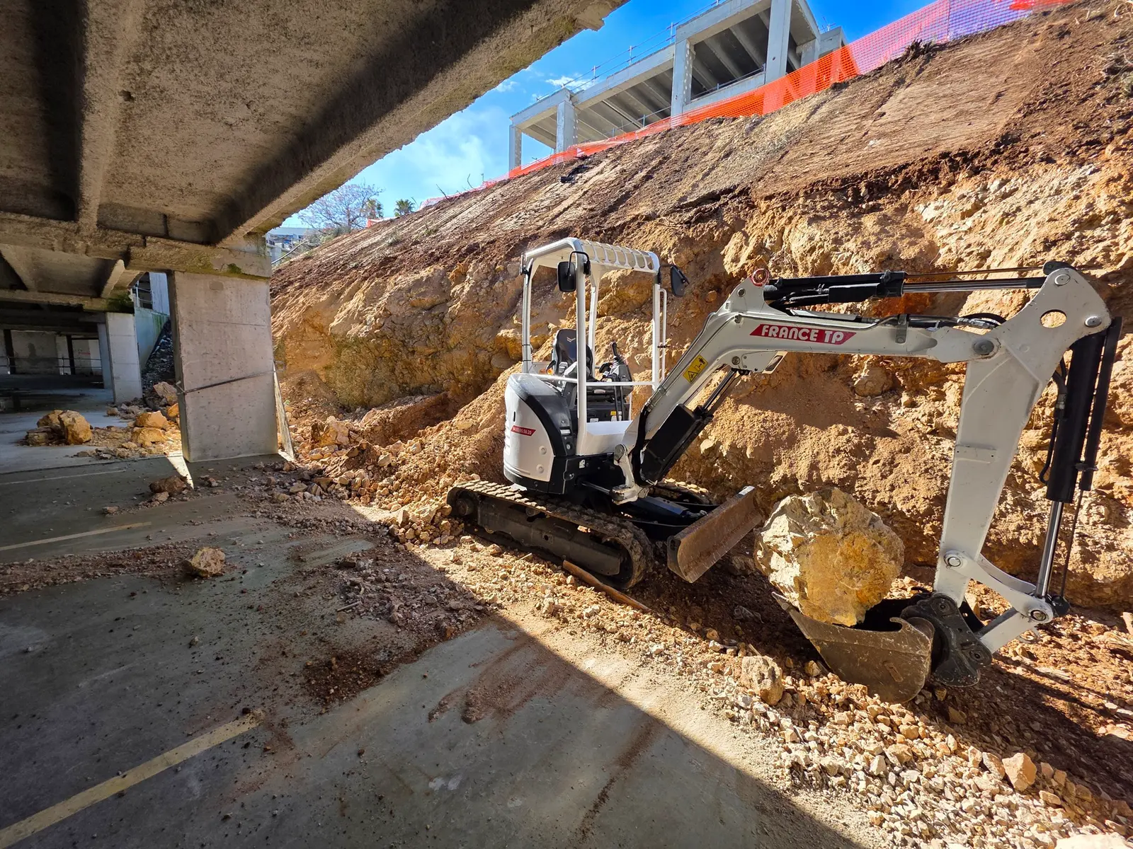 Terrassement d'un talus avec une mini-pelle CAT, agrandissement de surlargeur sous un ouvrage, déblaiement de roches.