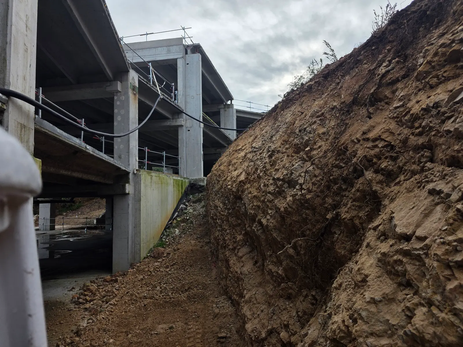 Terrassement d'un talus avec mini-pelle CAT pour agrandissement de surlargeur sous une structure en béton.